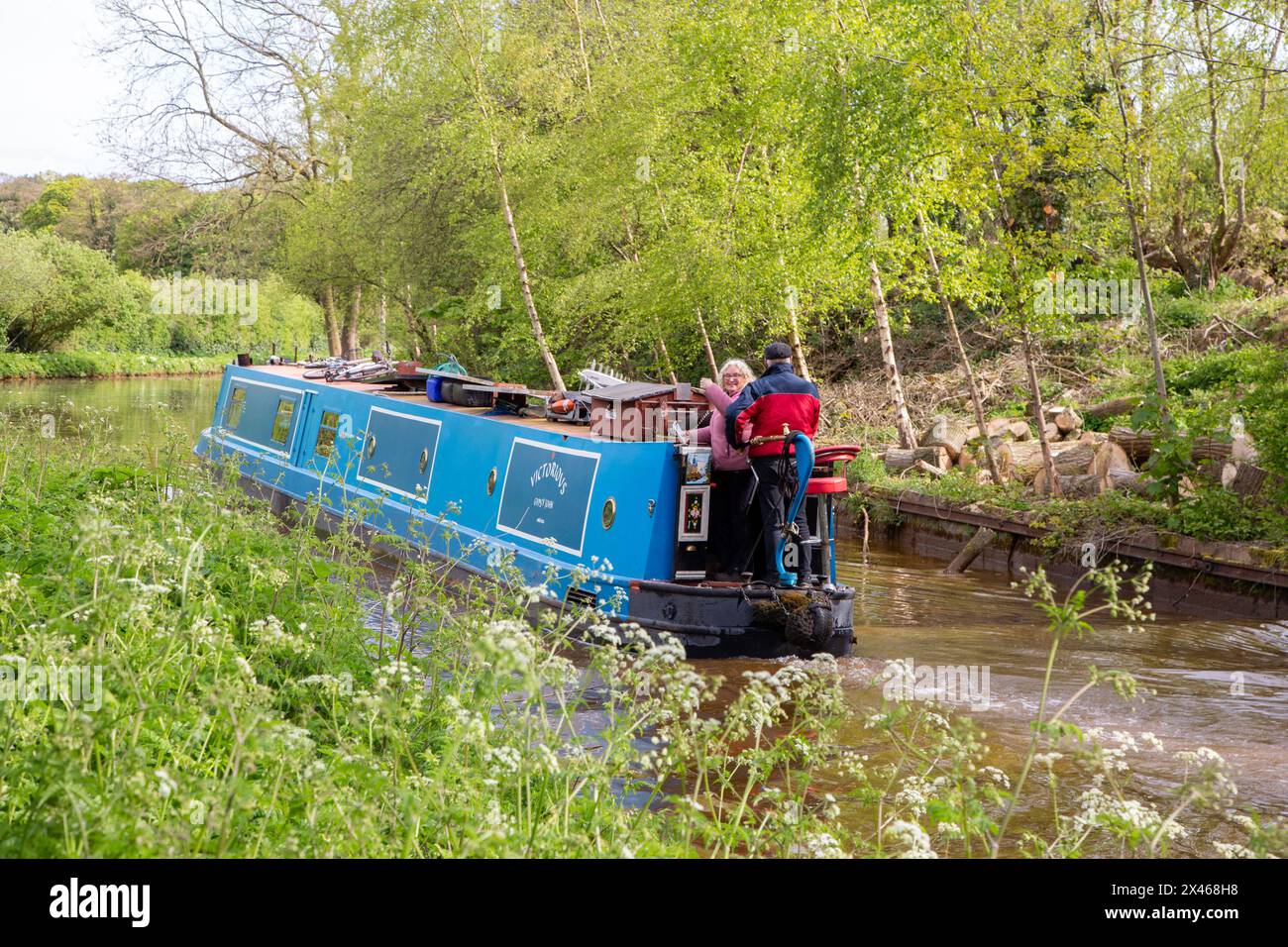 Couple on a canal narrowboat holiday passing through the Cheshire countryside near Rode Heath Cheshire on the Trent and Mersey canal Stock Photo