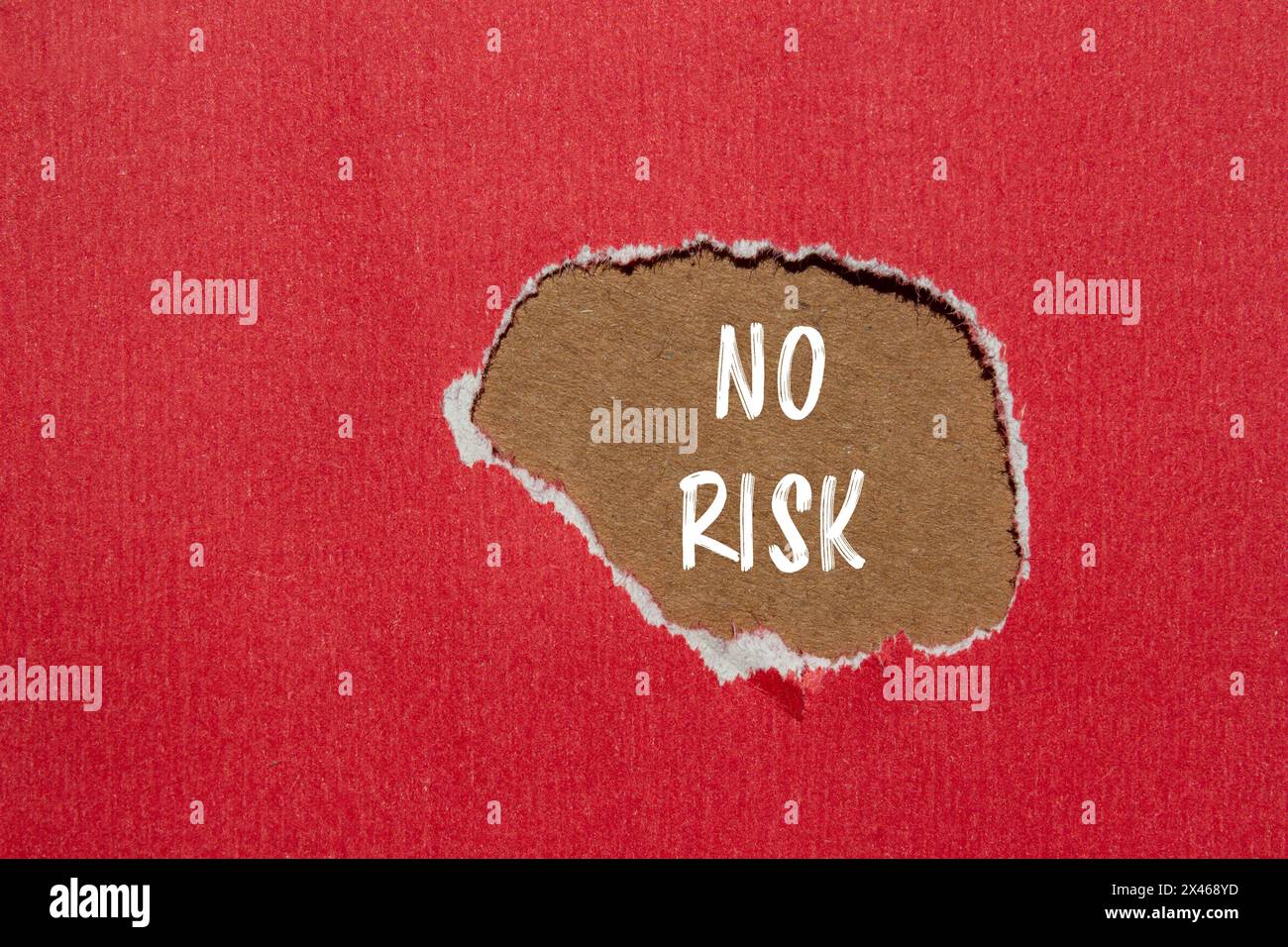 No risk written on ripped red paper with brown background. Conceptual no risk symbol. Copy space. Stock Photo