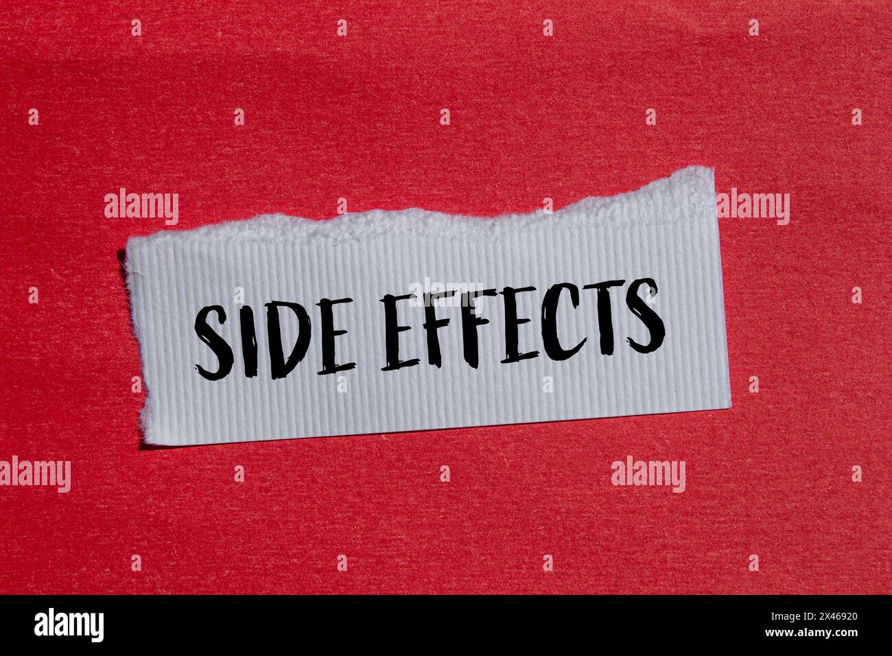 Side effects words written on ripped white paper with red background. Conceptual side effects symbol. Copy space. Stock Photo
