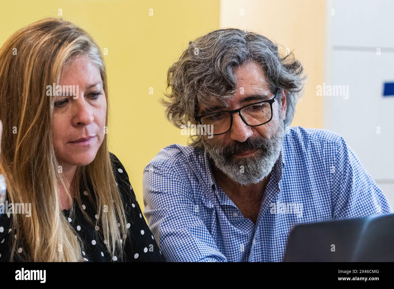 Focused mature colleagues sitting at table and using netbook while working on new project at workplace Stock Photo