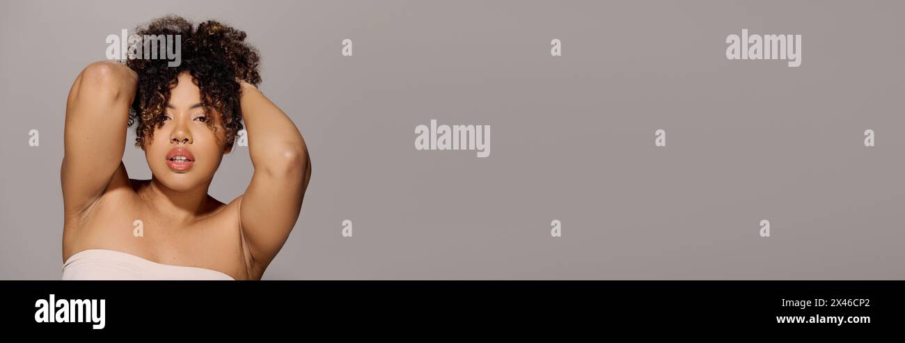 A beautiful young African American woman with curly hair is posing ...