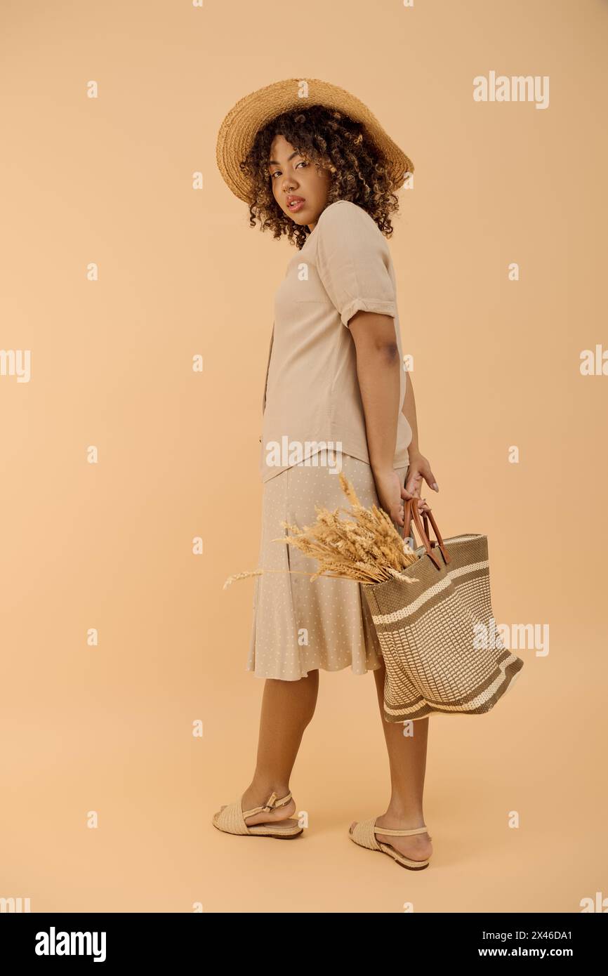 A beautiful young African American woman with curly hair dressed in a summer dress and sunhat, holding a basket. Stock Photo