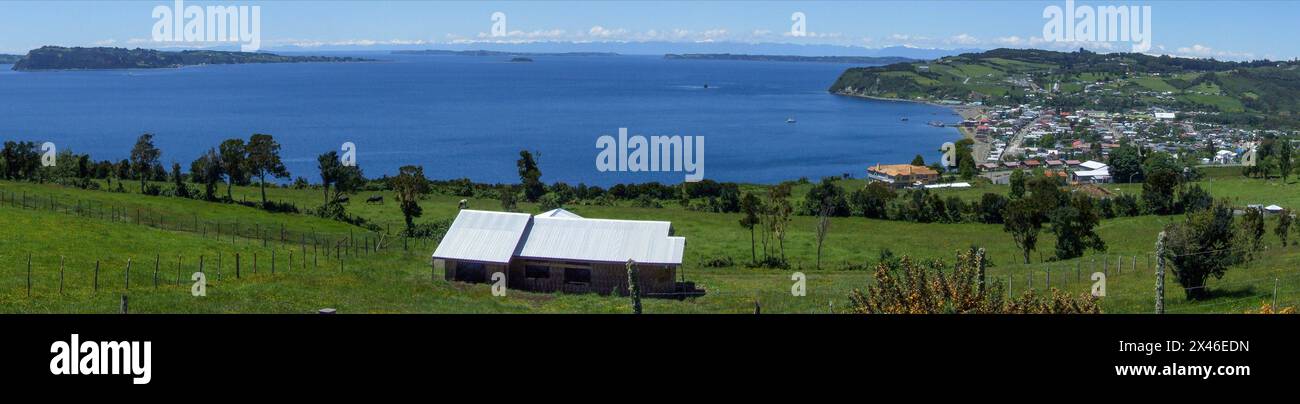 The town of Achao on the island of Quinchao in the Chiloe Archipeligo in Chile.  Behind are the snow-capped Andes Mountains on the mainland of Chile. Stock Photo