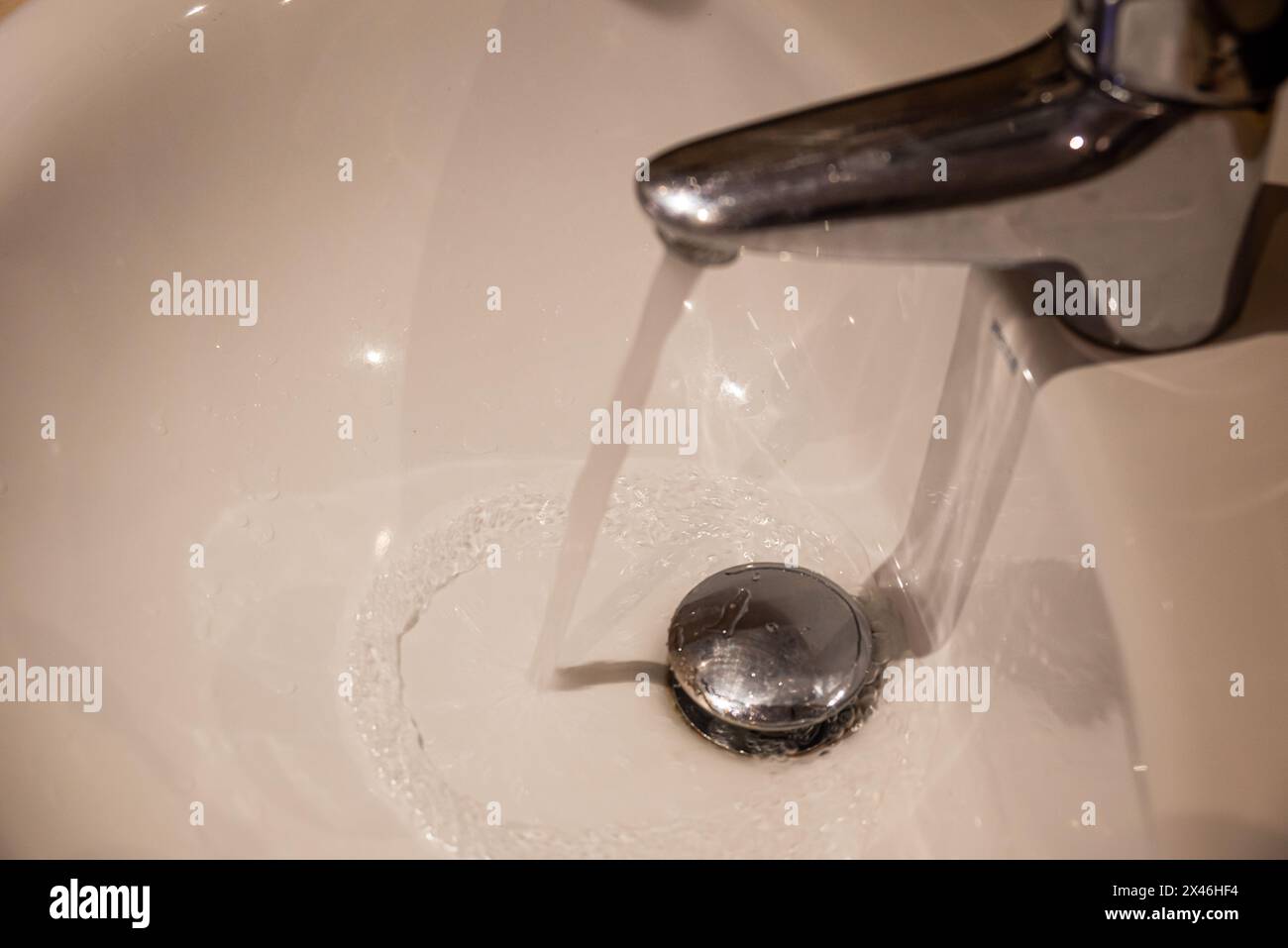 Liquid is flowing from the tap in the bathroom sink Stock Photo - Alamy