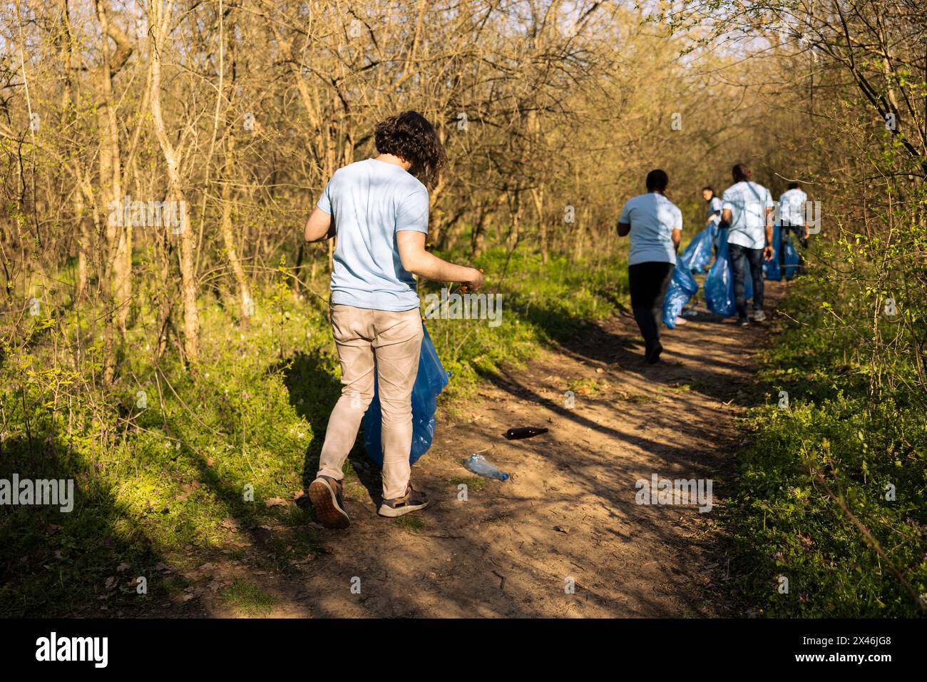 Young nature activist collecting junk with a long claw tool and garbage ...