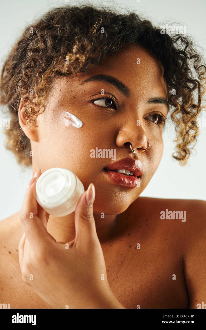 Woman gracefully applies cream to her face. Stock Photo