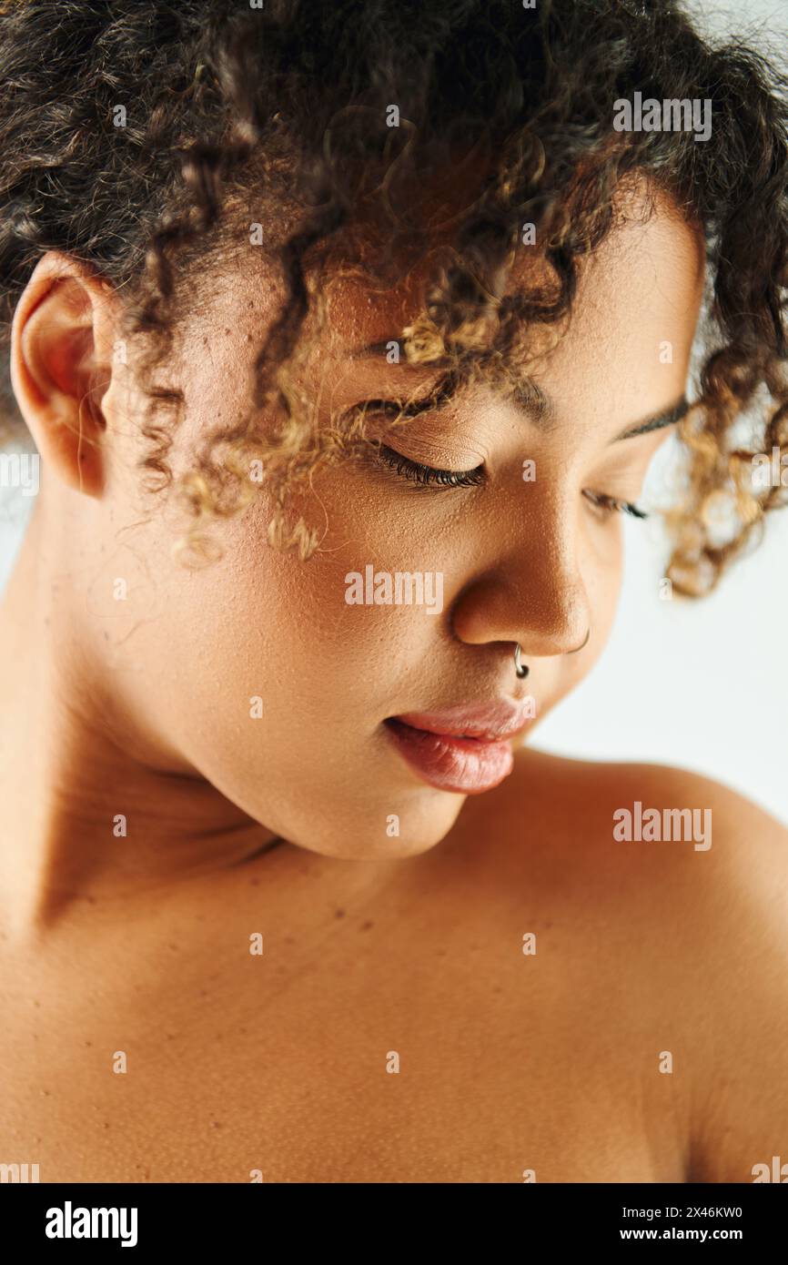 An African American woman with curly hair poses against a vibrant ...