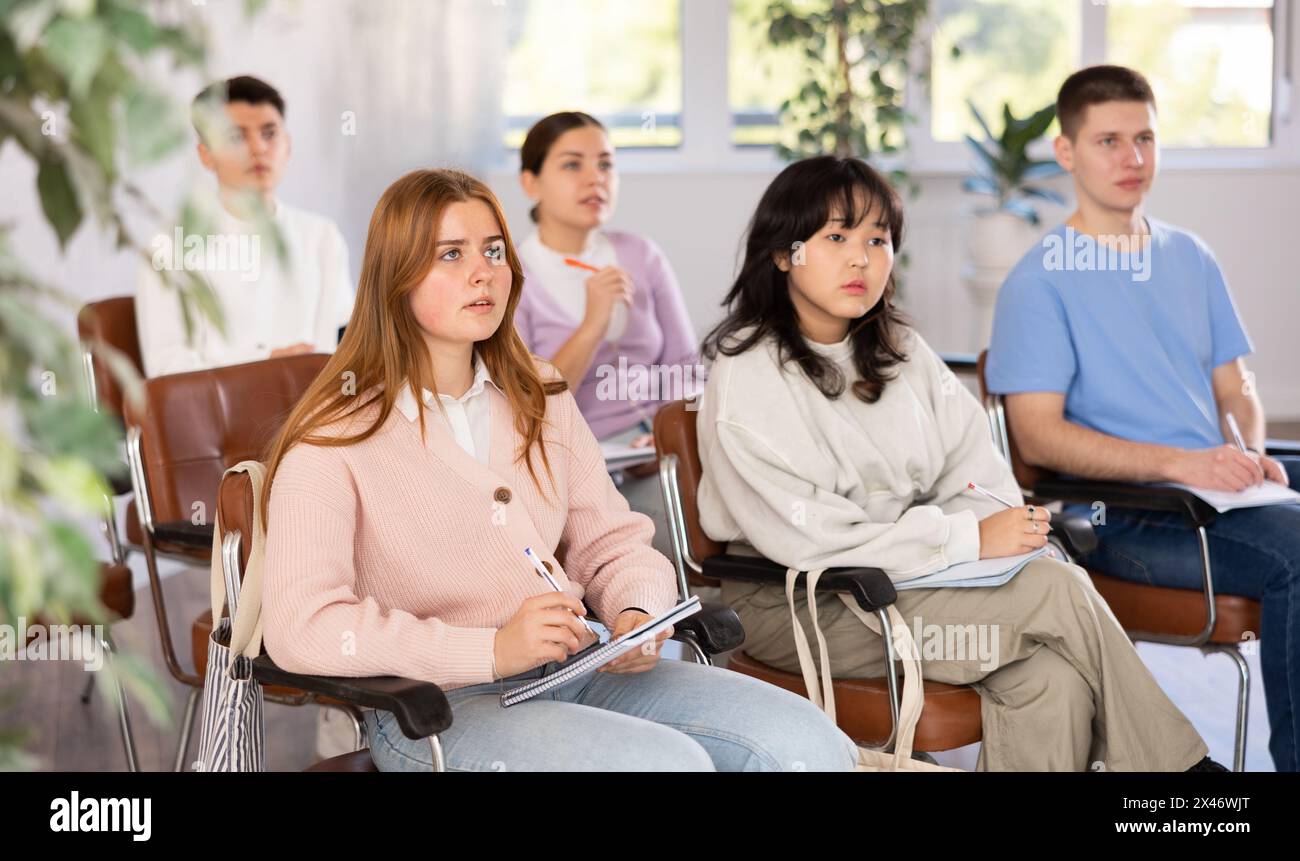 Young female student listening attentively to lecture in lecture hall Stock Photo