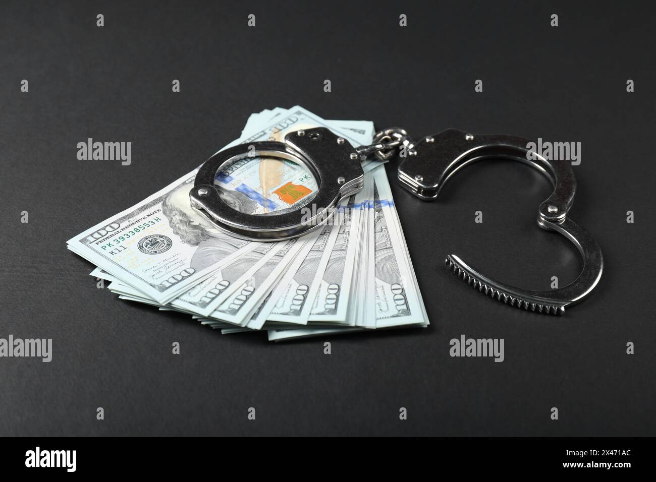 Dollars and metal handcuffs on grey table Stock Photo