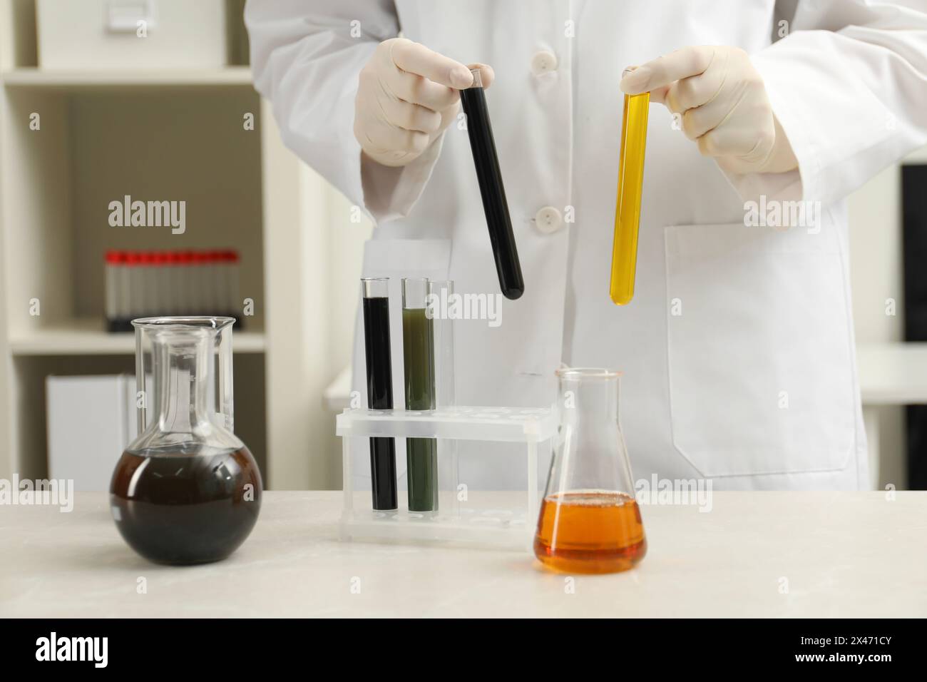 Laboratory worker holding test tubes with different types of crude oil