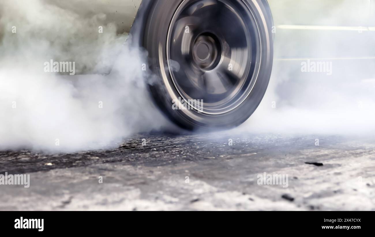 Drag racing car burning tire at starting line in race track Stock Photo