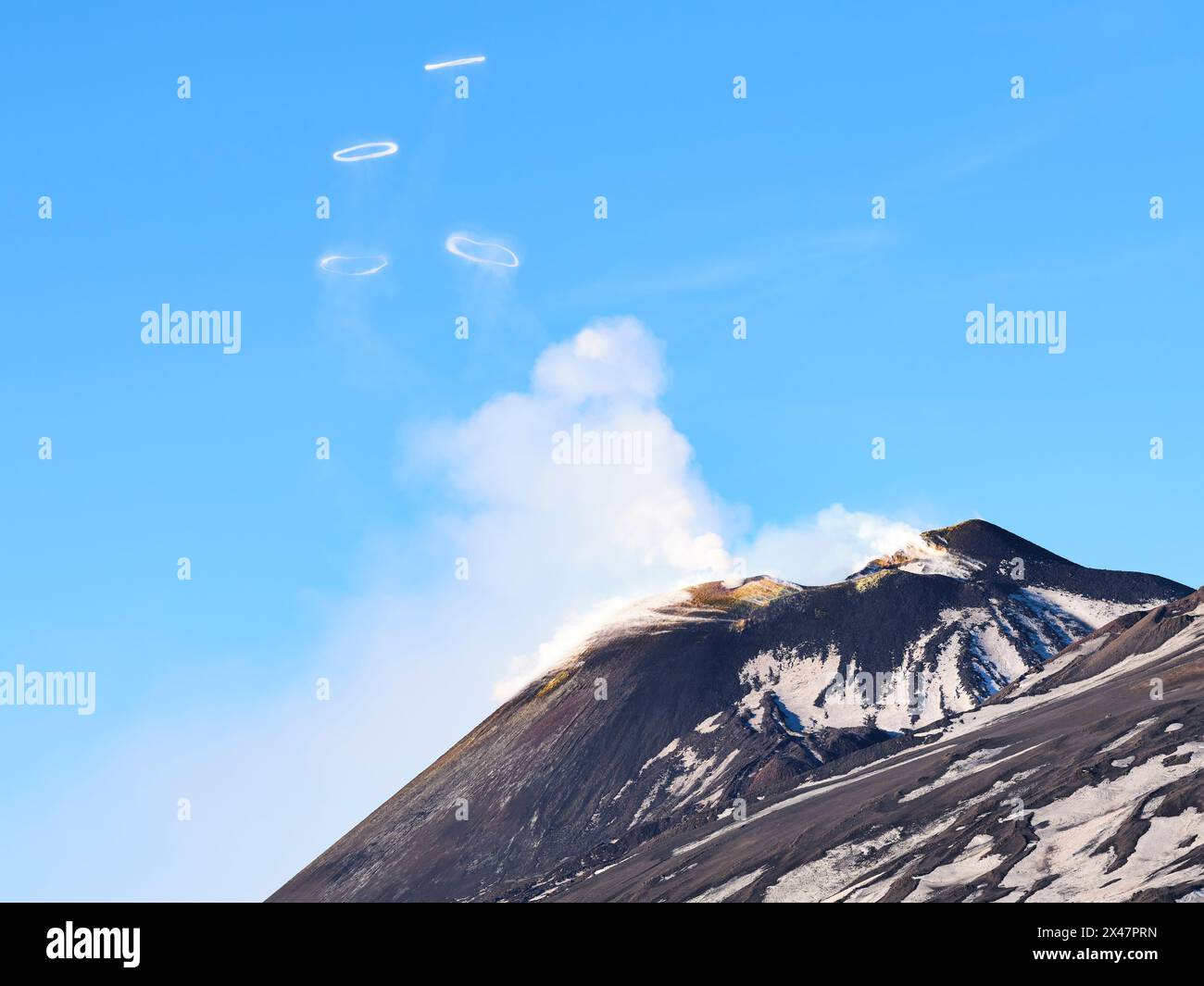 AERIAL VIEW. Summit of Mount Etna blowing volcanic smoke rings (vortex rings). it is a rare occurrence. Metropolitan City of Catania, Sicily, Italy. Stock Photo