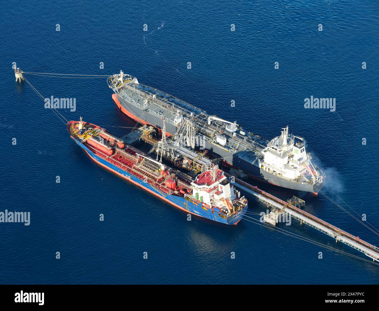AERIAL VIEW. Oil tankers alongside a pipeline at the Milazzo Refinery. Metropolitan City of Messina, Sicily, Italy. Stock Photo