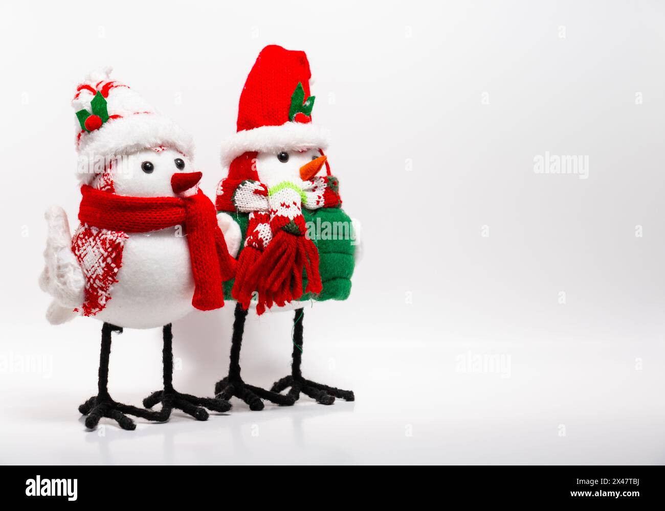 two handcrafted bird Christmas holiday yule decorations wearing scarves winter white background with negative space Stock Photo