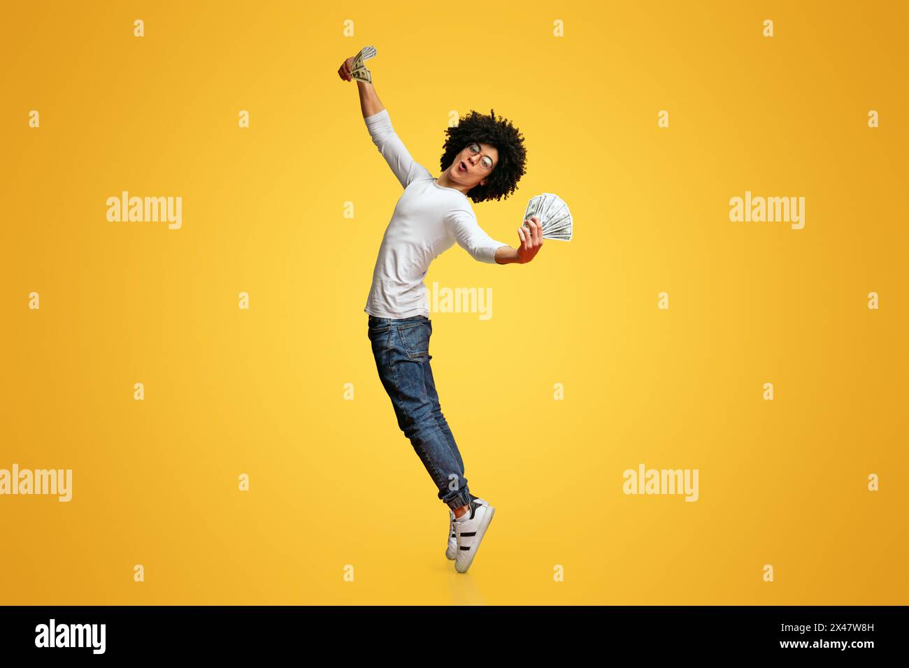 Young excited black man dancing with dollars Stock Photo