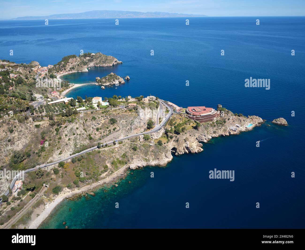 AERIAL VIEW. The rocky promontories of Taormina jutting out into the Ionian Sea. Metropolitan City of Messina, Sicily, Italy. Stock Photo