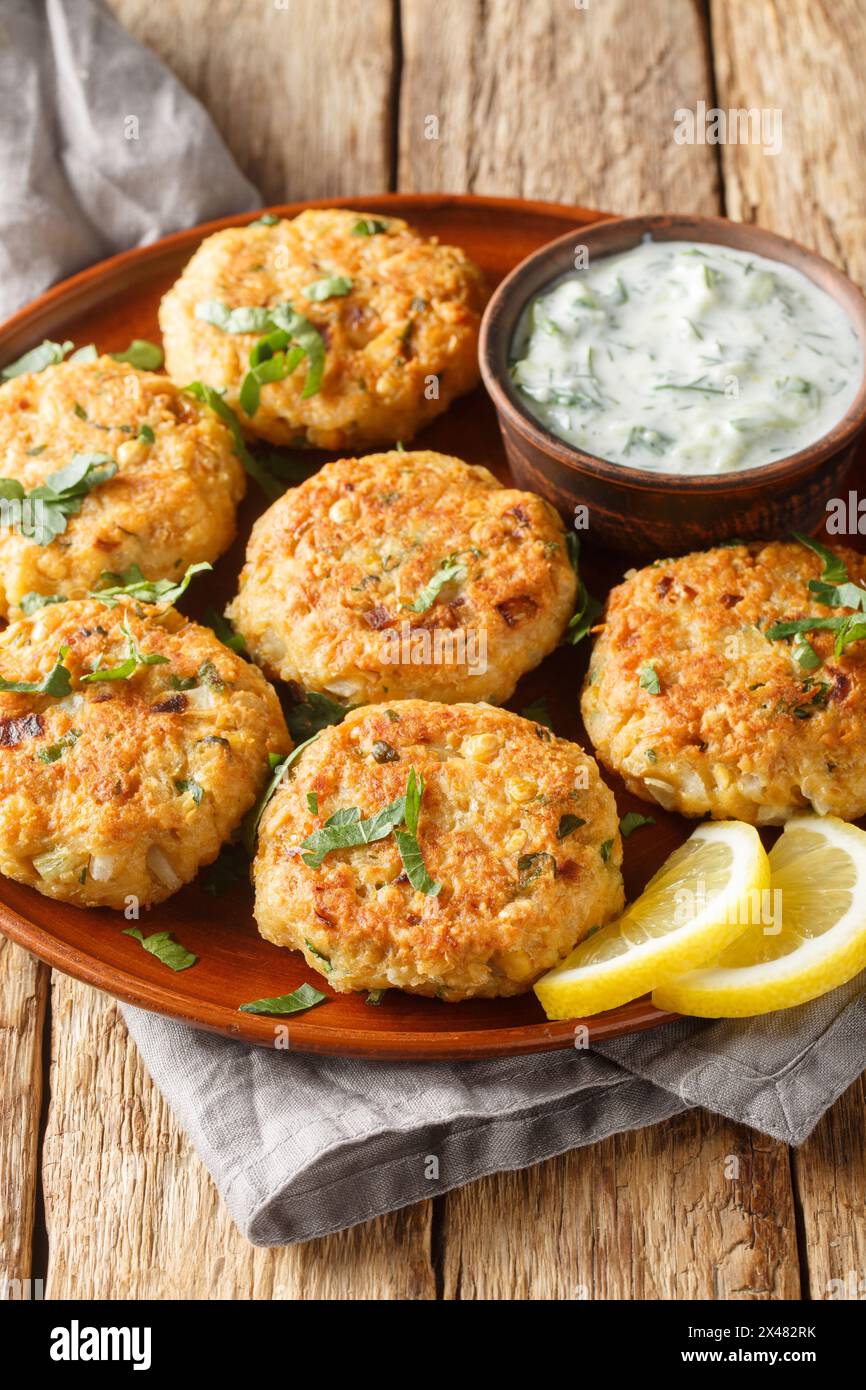 Chickpea fritters with tzatziki sauce close-up in a plate on a wooden table. Vertical Stock Photo
