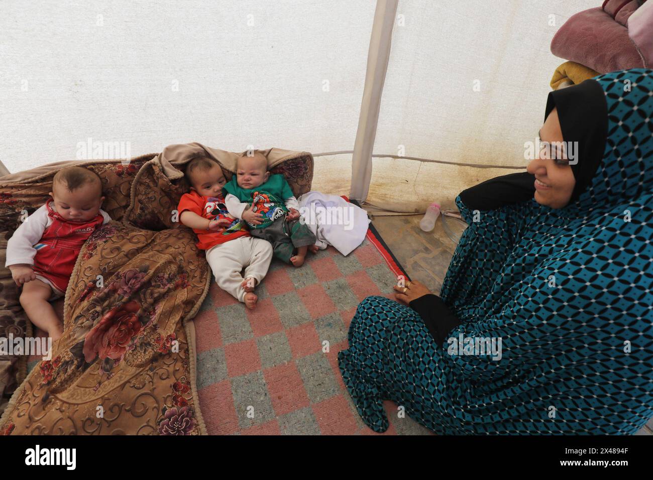 A Palestinian mother and her triplets shelter in their tent at a ...