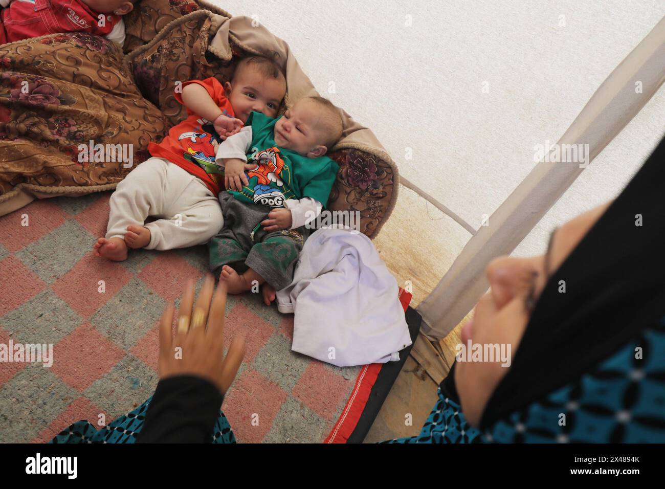 A Palestinian mother and her triplets shelter in their tent at a ...