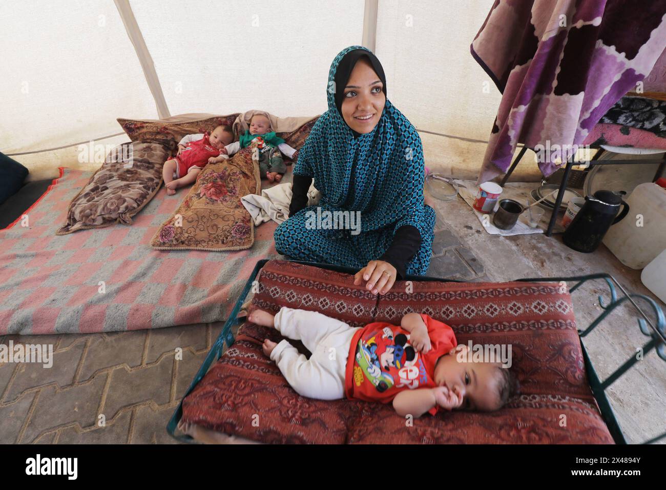 A Palestinian mother and her triplets shelter in their tent at a ...