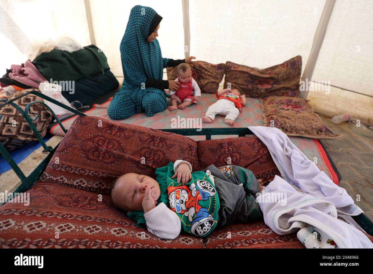 A Palestinian mother and her triplets shelter in their tent at a ...