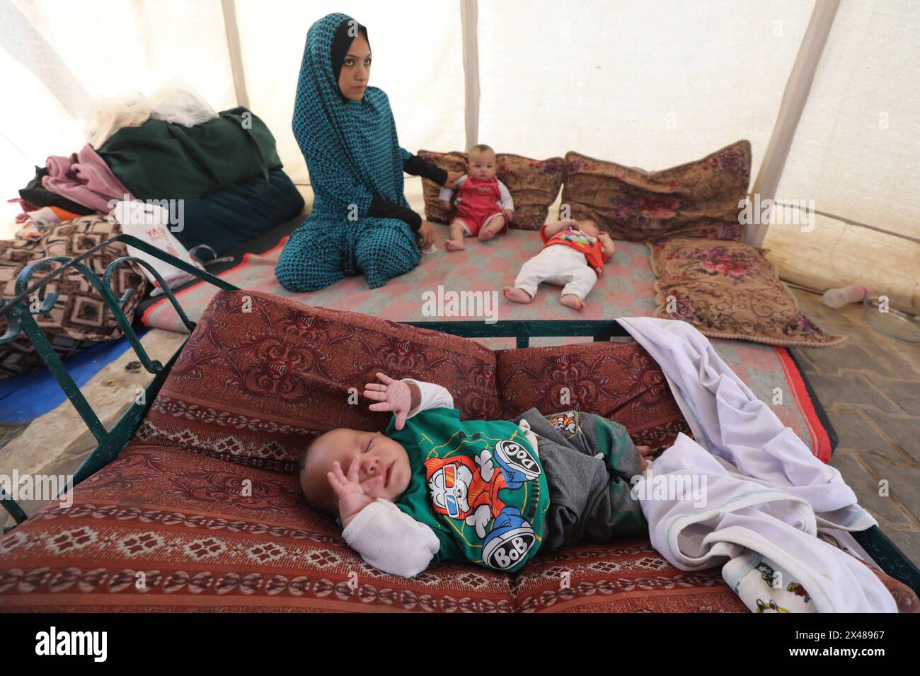 A Palestinian mother and her triplets shelter in their tent at a ...