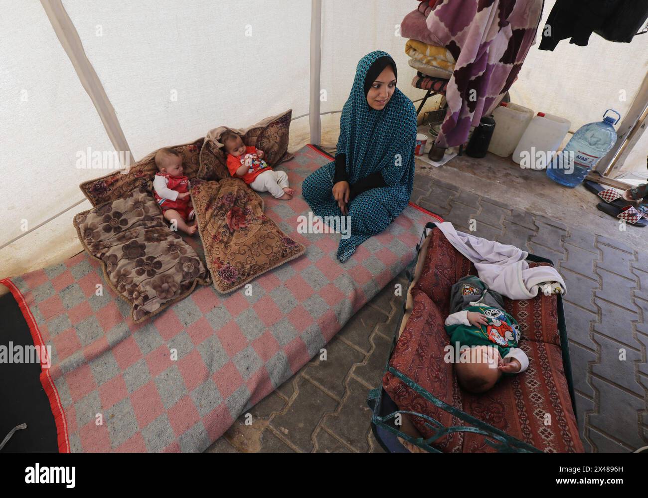 A Palestinian mother and her triplets shelter in their tent at a ...