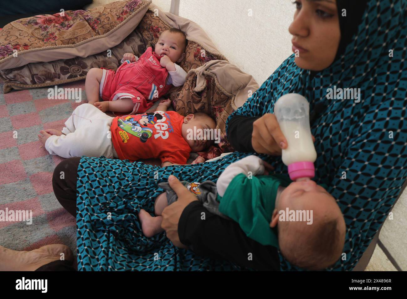A Palestinian mother and her triplets shelter in their tent at a ...