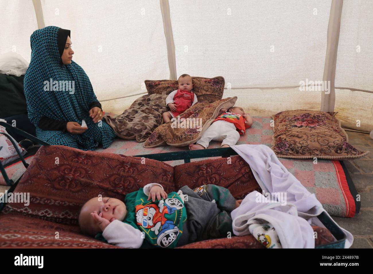 A Palestinian mother and her triplets shelter in their tent at a ...