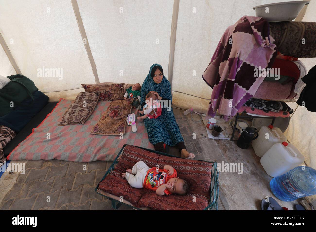 A Palestinian mother and her triplets shelter in their tent at a ...