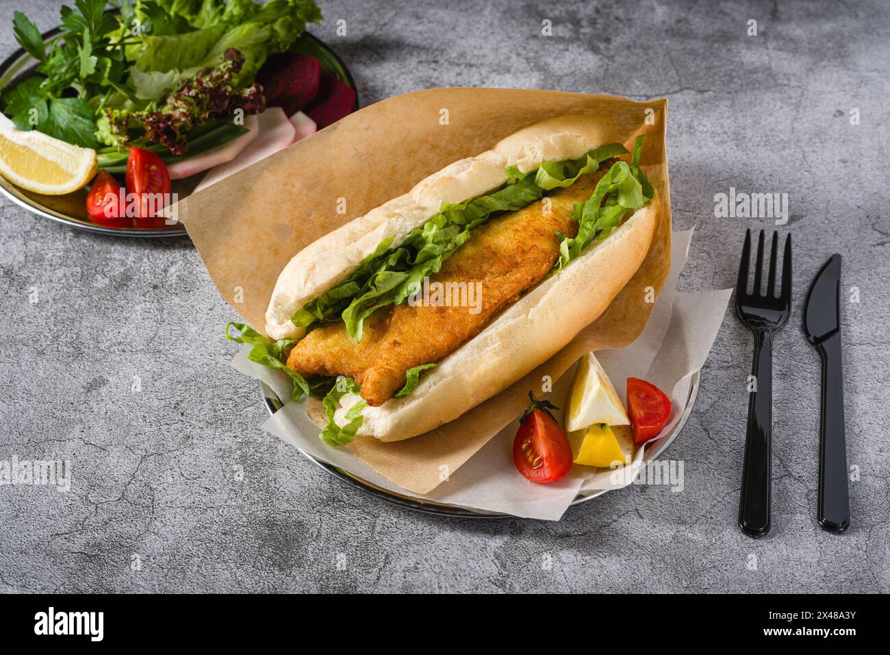 Fried fish sandwich with greens on the stone table. Turkish name Balik Ekmek Stock Photo