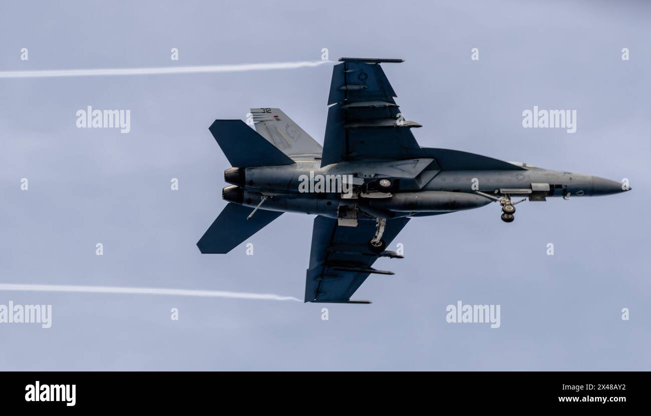 SOUTH CHINA SEA (April 29, 2024) An F/A-18E Super Hornet, attached to the “Blue Blasters” of Strike Fighter Squadron (VFA) 34, flies over the Nimitz-c Stock Photo