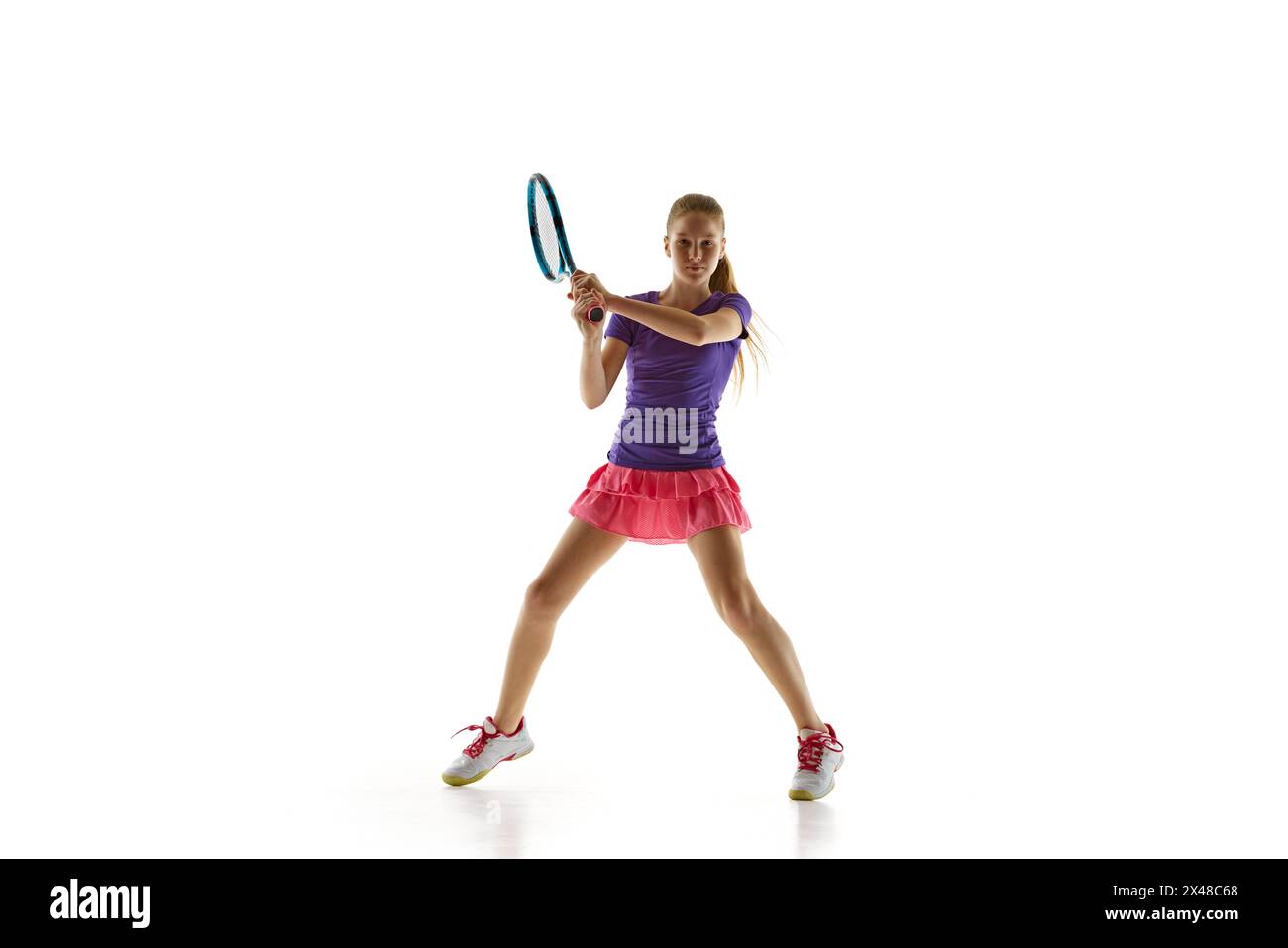 Sporty teenage tennis player in uniform ready to hit twohanded
