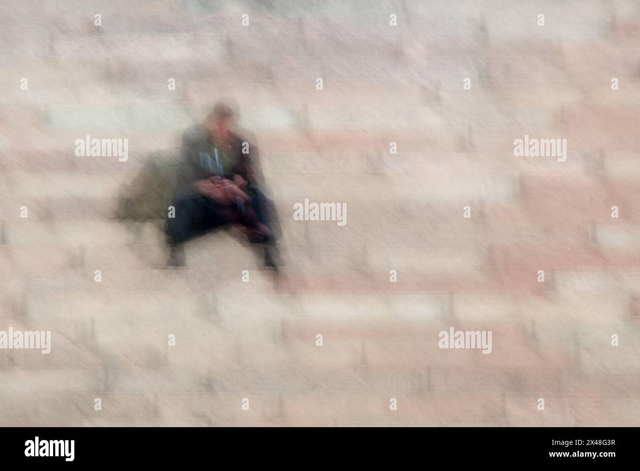Abstract of a man sitting on stone steps and looking at a phone in his ...
