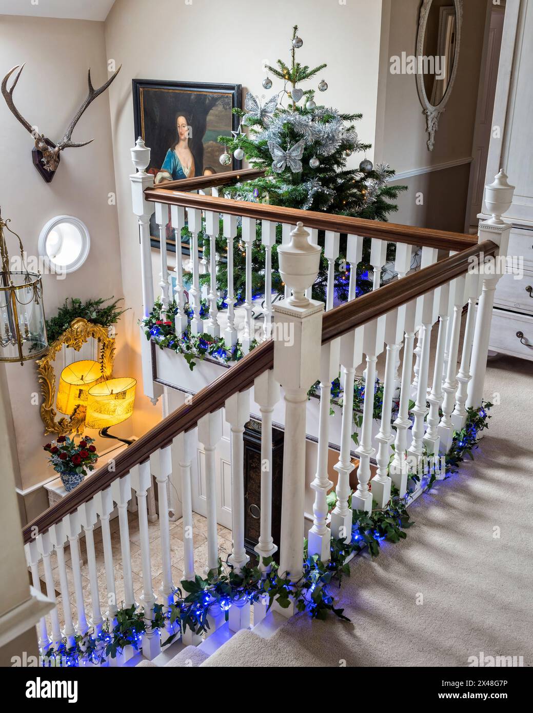 Double height staircase decorated with holly and lights in Dorset ...