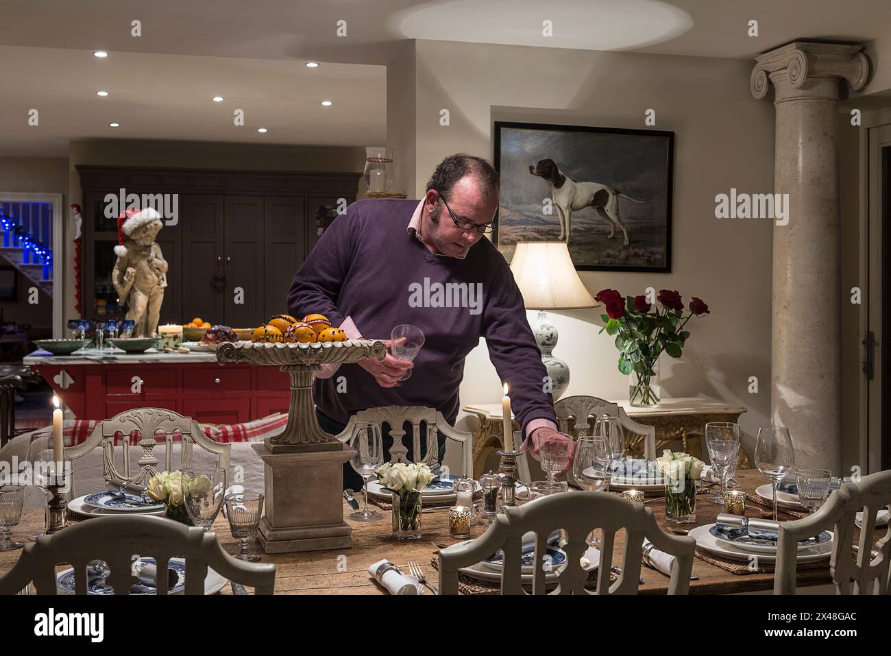 Man laying table in Dorset family home at Christmas, England, UK Stock Photo