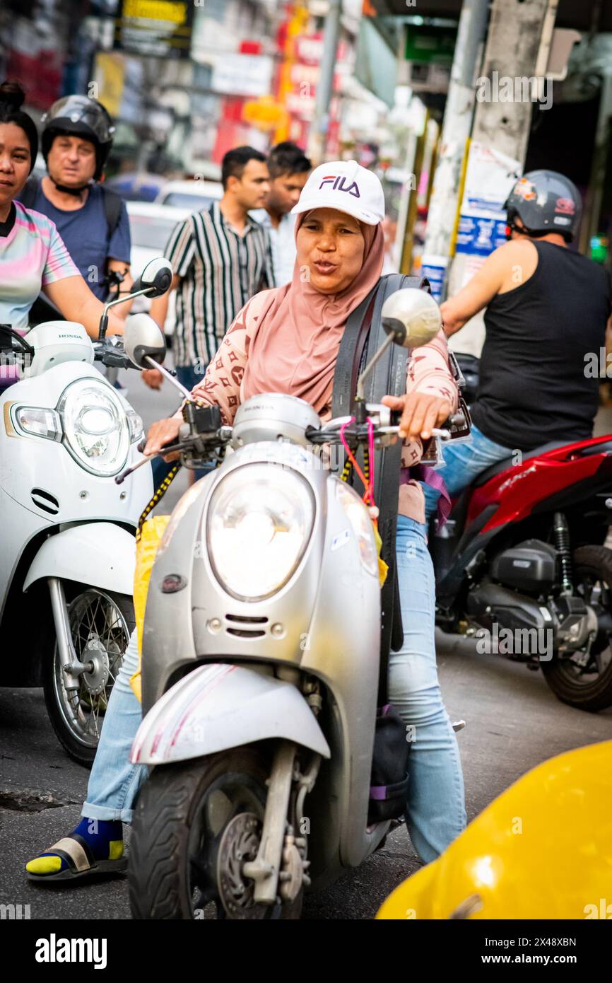 A Thai woman rides her scooter through the busy streets of Pattaya