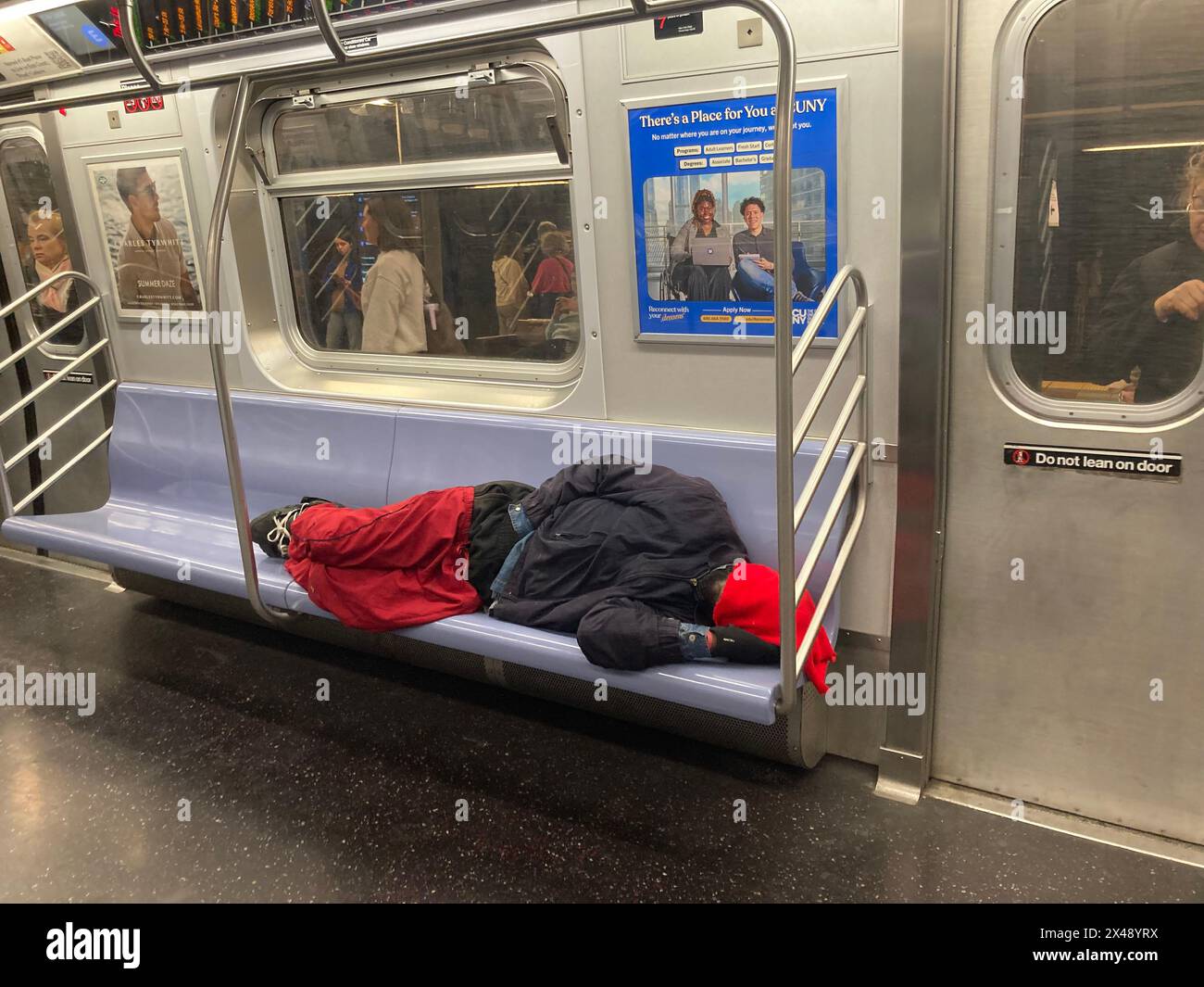 Homeless man asleep on a subway train in New York on Sunday Morning, April 28, 2024. (© Frances M. Roberts) Stock Photo