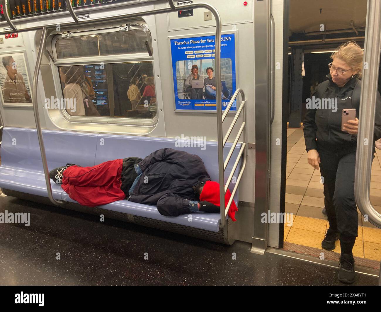 Homeless man asleep on a subway train in New York on Sunday Morning, April 28, 2024. (© Frances M. Roberts) Stock Photo