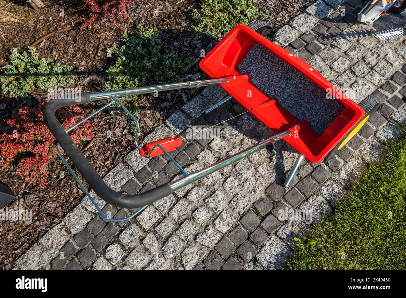 Manual Garden Lawn Fertilize Distributor on a Granite Path Top View. Gardening Theme. Stock Photo