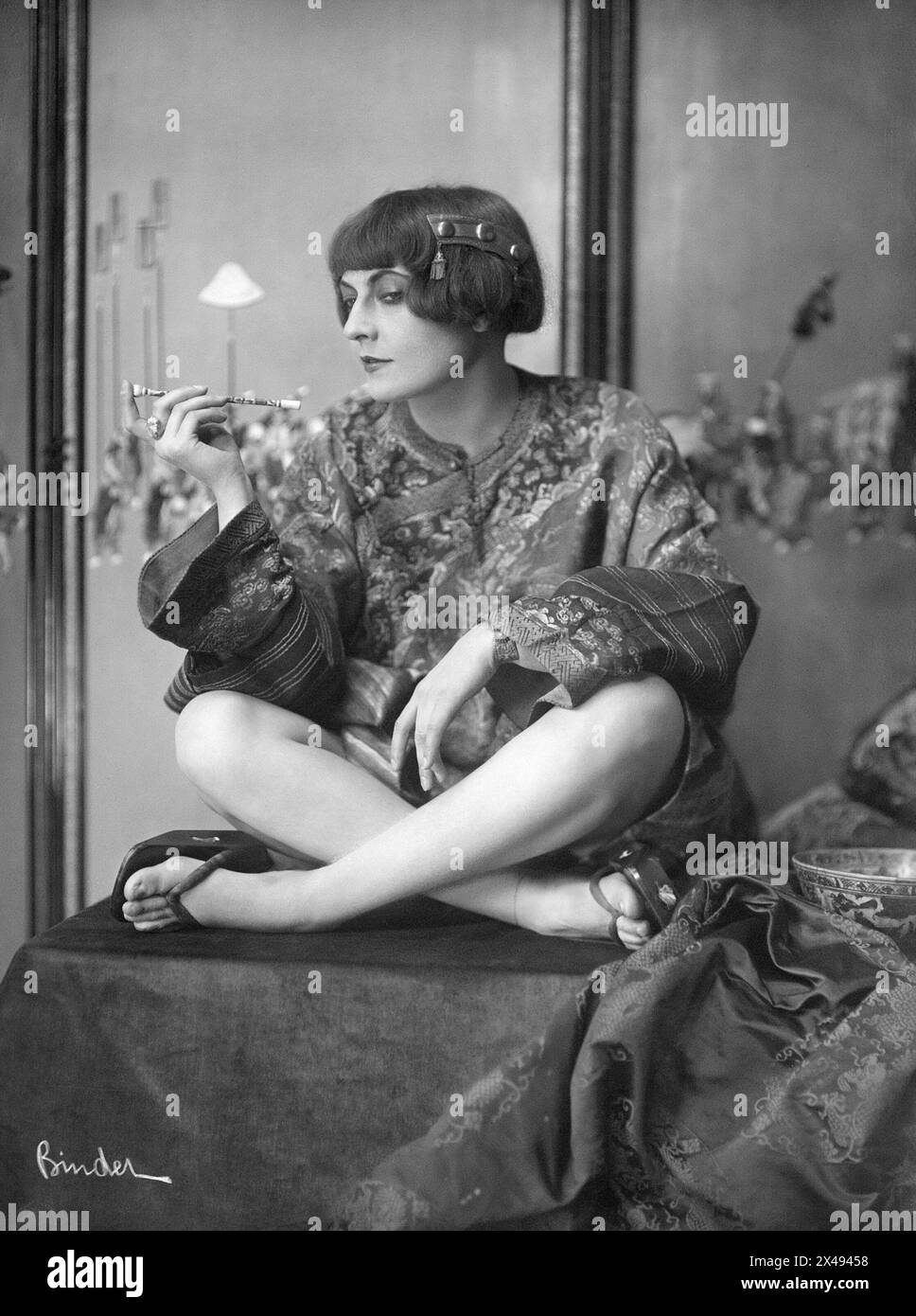 Portrait of the dancer Grit Hegesa with a cigarette holder sitting cross-legged - 1921 Stock Photo