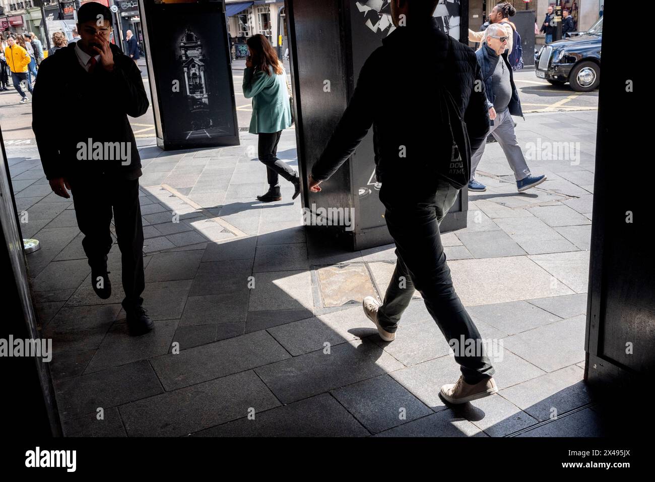 Pedestrians walk between light and shadow in the capital's West End, on 30th April 2024, in London, England. Stock Photo
