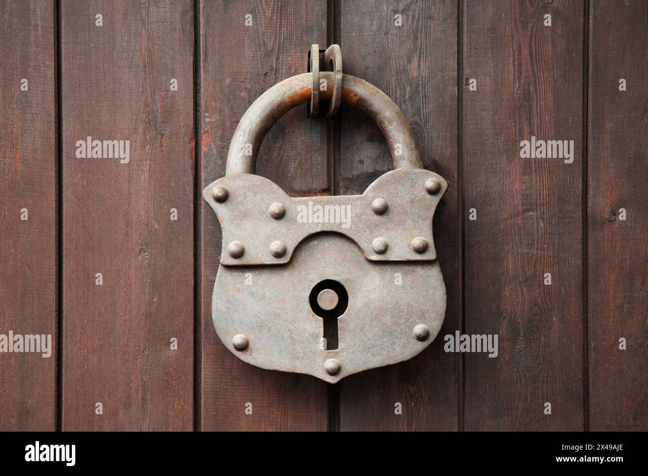 Old rusty padlock on a wooden door.   Wooden Gate With Large Hinged Iron Lock In The Village . close up view Stock Photo