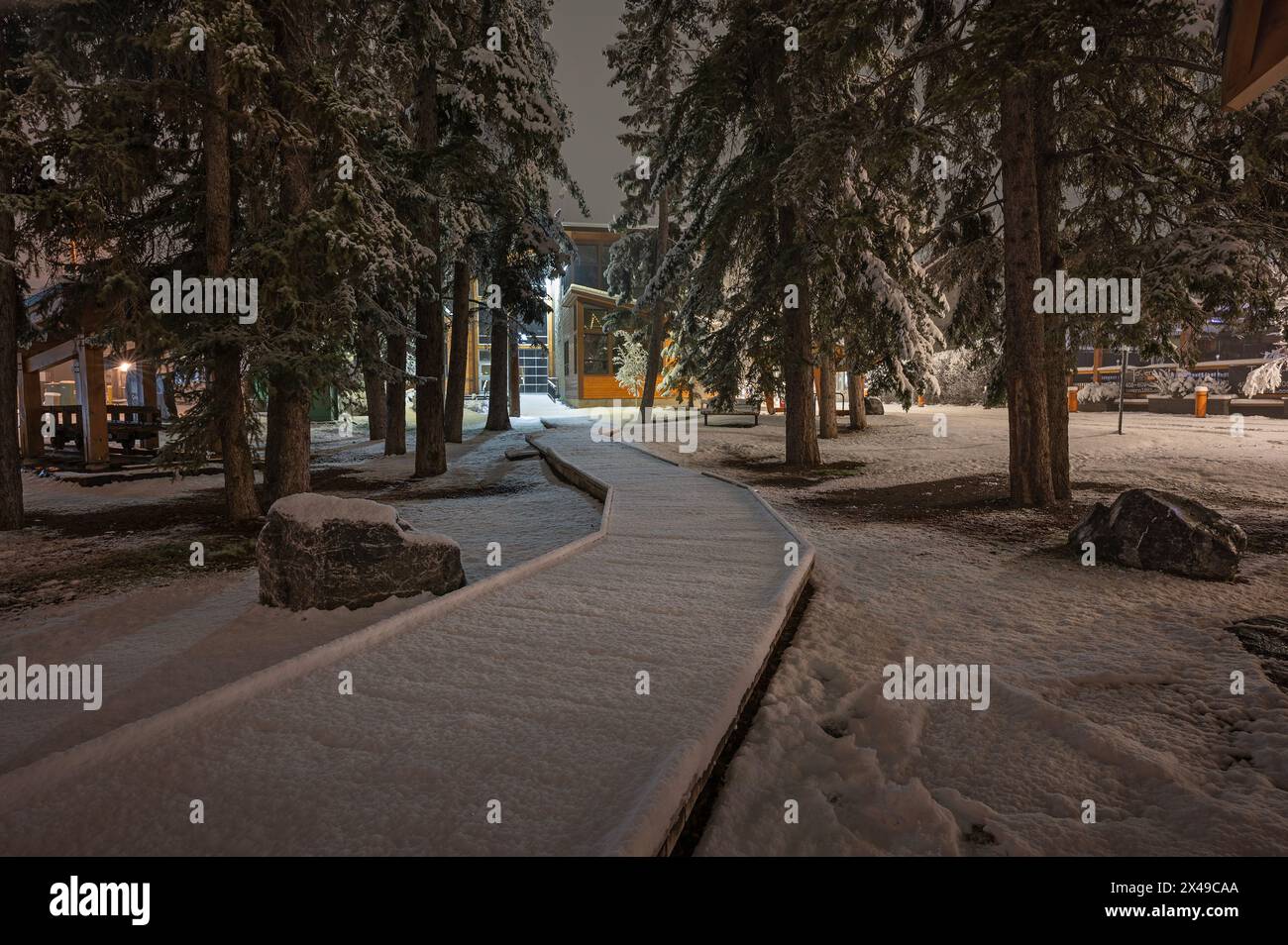 Night view of a snow-covered wooden walkway through Friendship Park in Canmore, Alberta, Canada Stock Photo