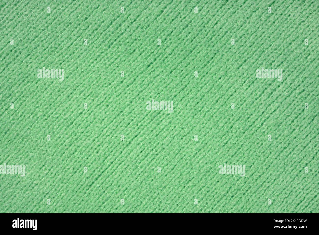 Green knitted woolen jersey fabric with diagonal weaving, sweater, pullover texture background. Fabric abstract backdrop, cloth wallpaper Stock Photo