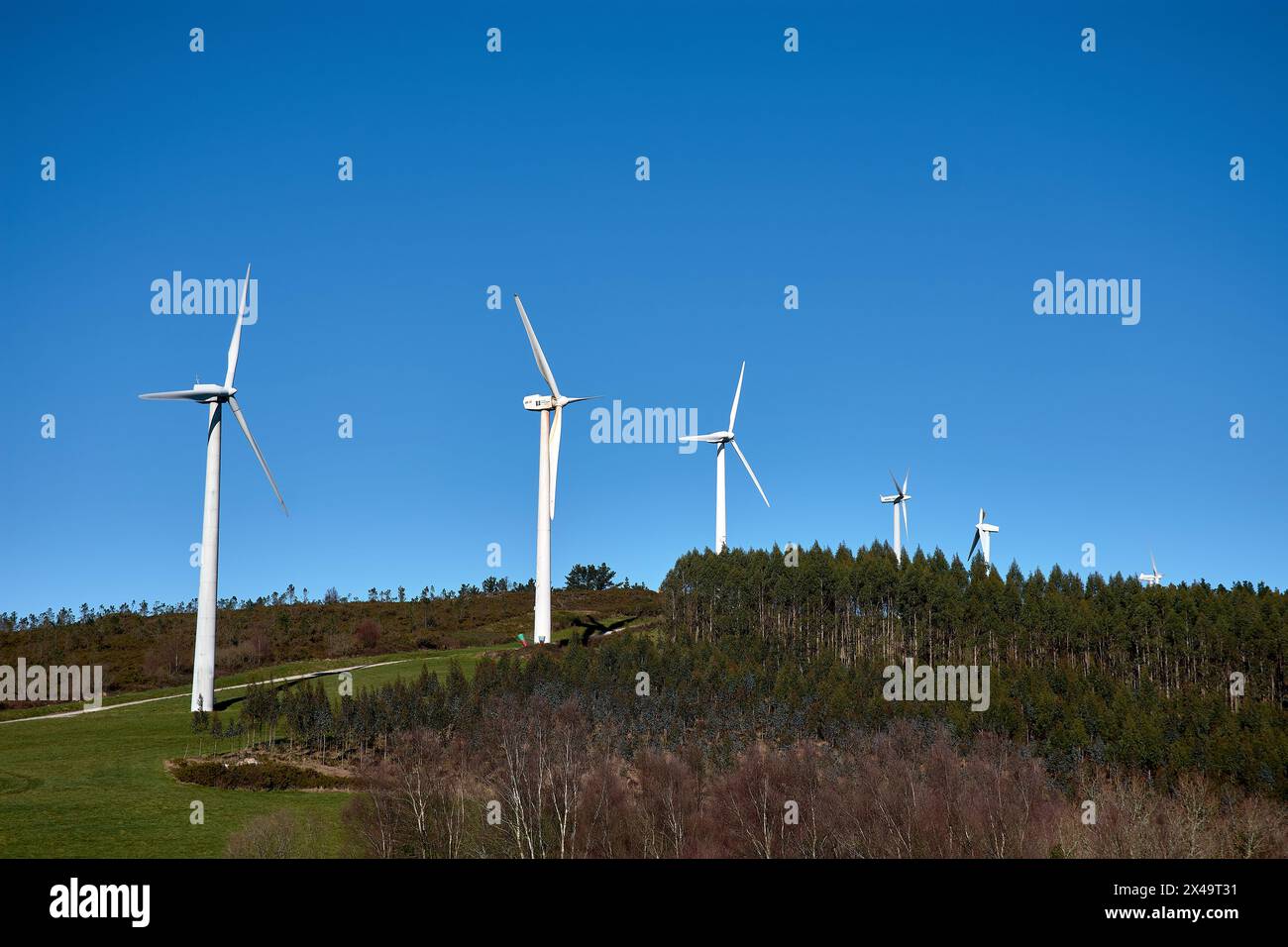 Wind turbines in a beautiful sunny mountain landscape. Curved path through the mountain Wind Farm. Green energy generation. Wind farm ecological field Stock Photo