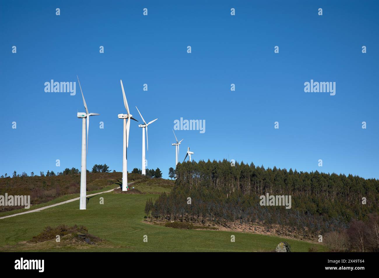 Wind turbines in a beautiful sunny mountain landscape. Curved path through the mountain Wind Farm. Green energy generation. Wind farm ecological field Stock Photo