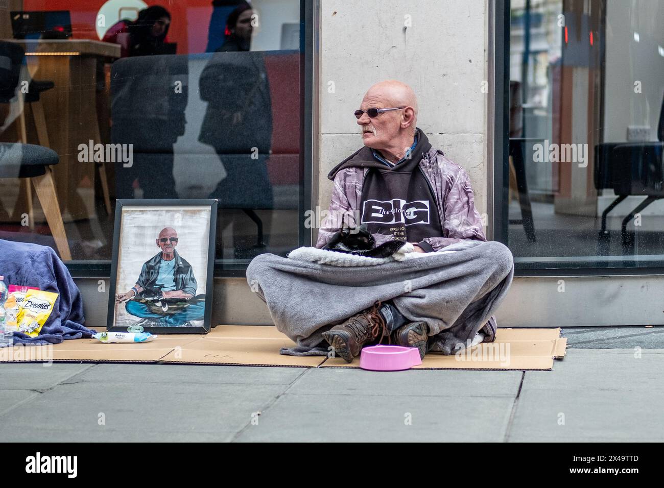 LONDON- APRIL 4th, 2024: A homeless man with a cat on Oxford Street in the West End Stock Photo