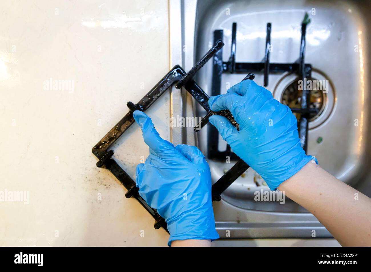 Cleaning the cast iron grill of the gas hob with a dishwashing wire