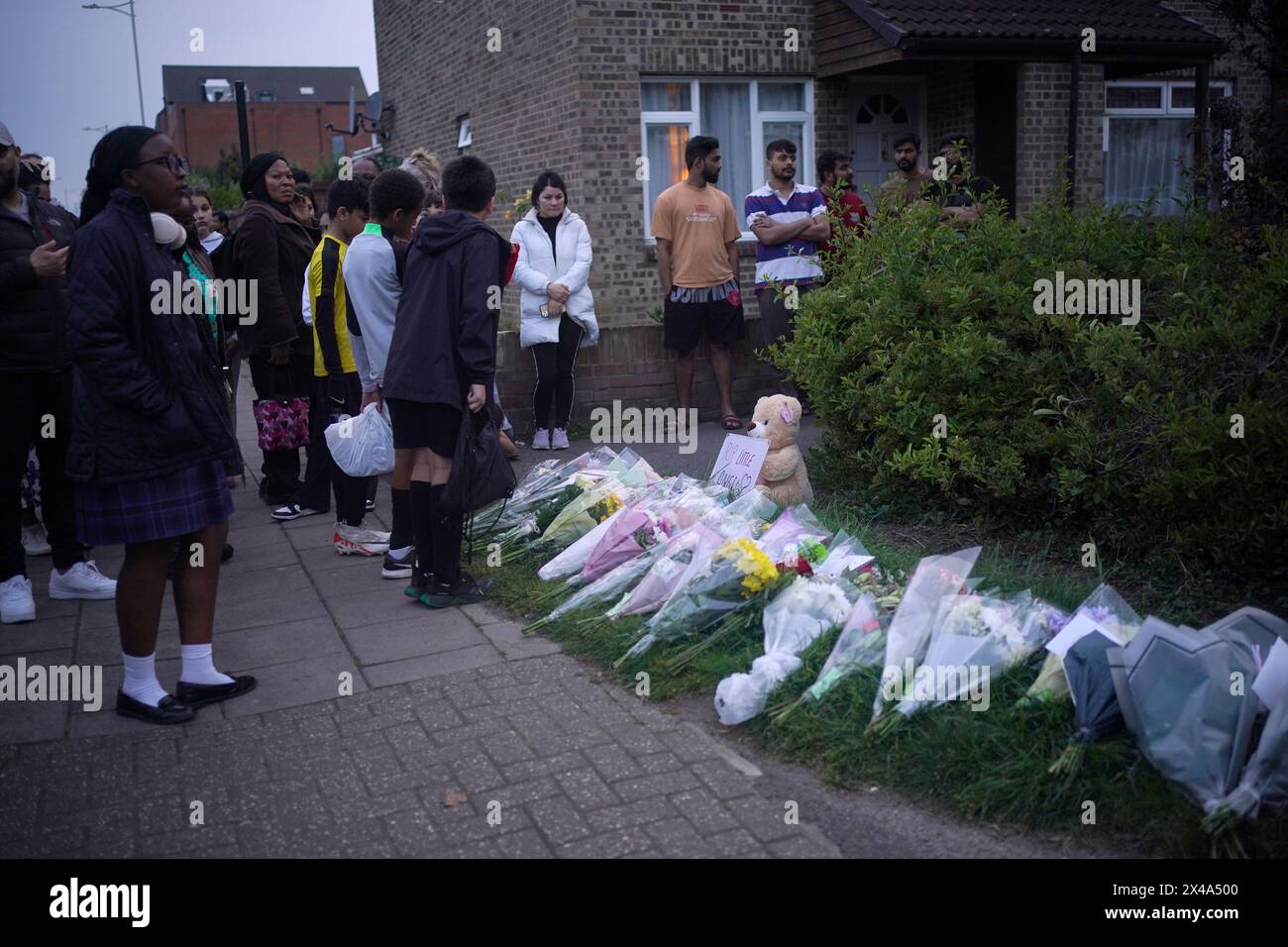 People looking at floral tributes in Hainault, north east London, where 14-year-old Daniel Anjorin, was killed in a sword attack on Tuesday, that saw four others injured, including two Metropolitan Police officers. The teenager, who was fatally injured as he walked to school on Tuesday morning, was a pupil at the same school as Grace O'Malley-Kumar who was stabbed to death in Nottingham last year. Picture date: Wednesday May 1, 2024. Stock Photo